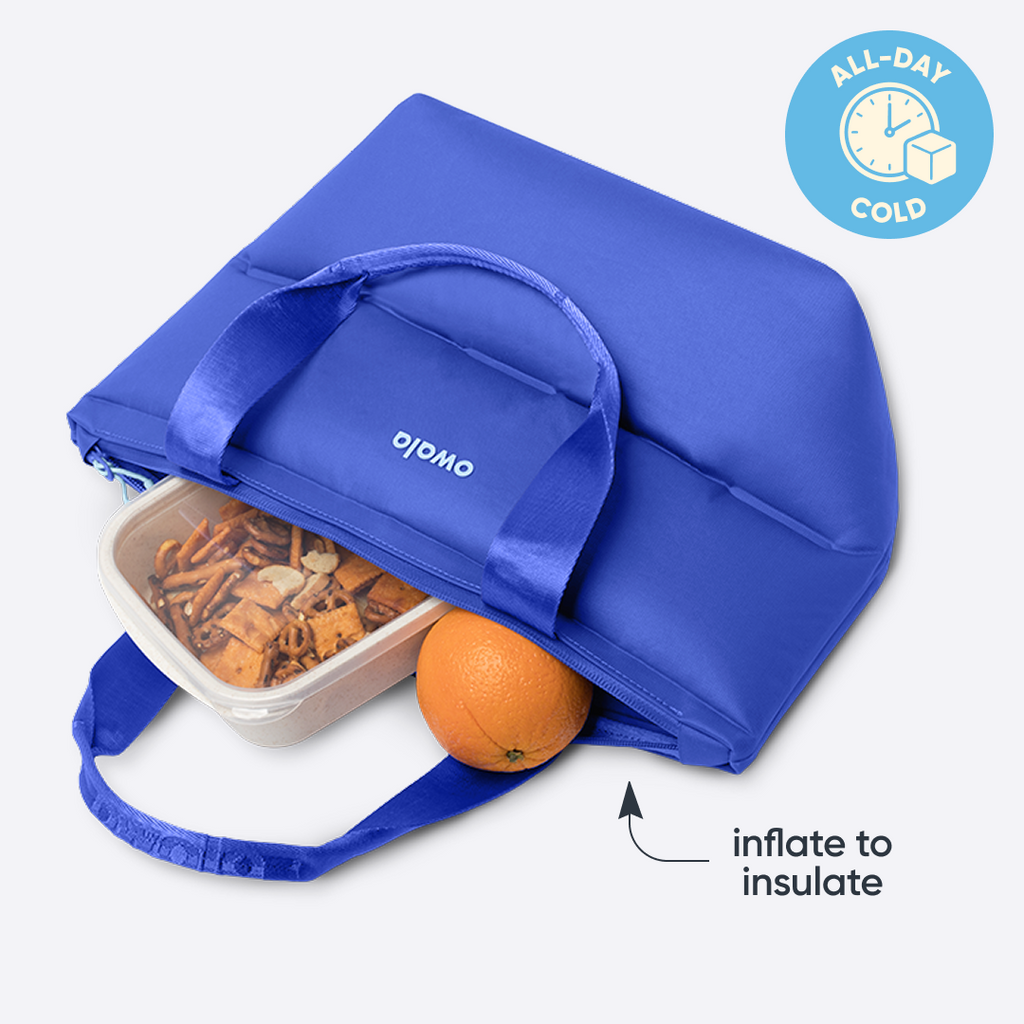Owala Puffer Mini in Al Fresco, cobalt blue puffy tote packed open with a food container and an orange inside, with badge reading "ALL-DAY COLD" and text reading "inflate to insulate"